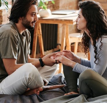 couple talking and listening on a bed
