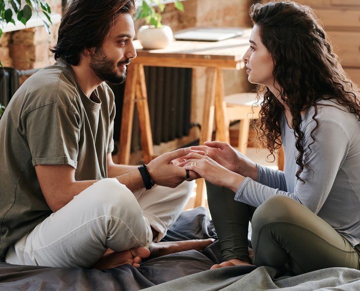couple talking and listening on a bed