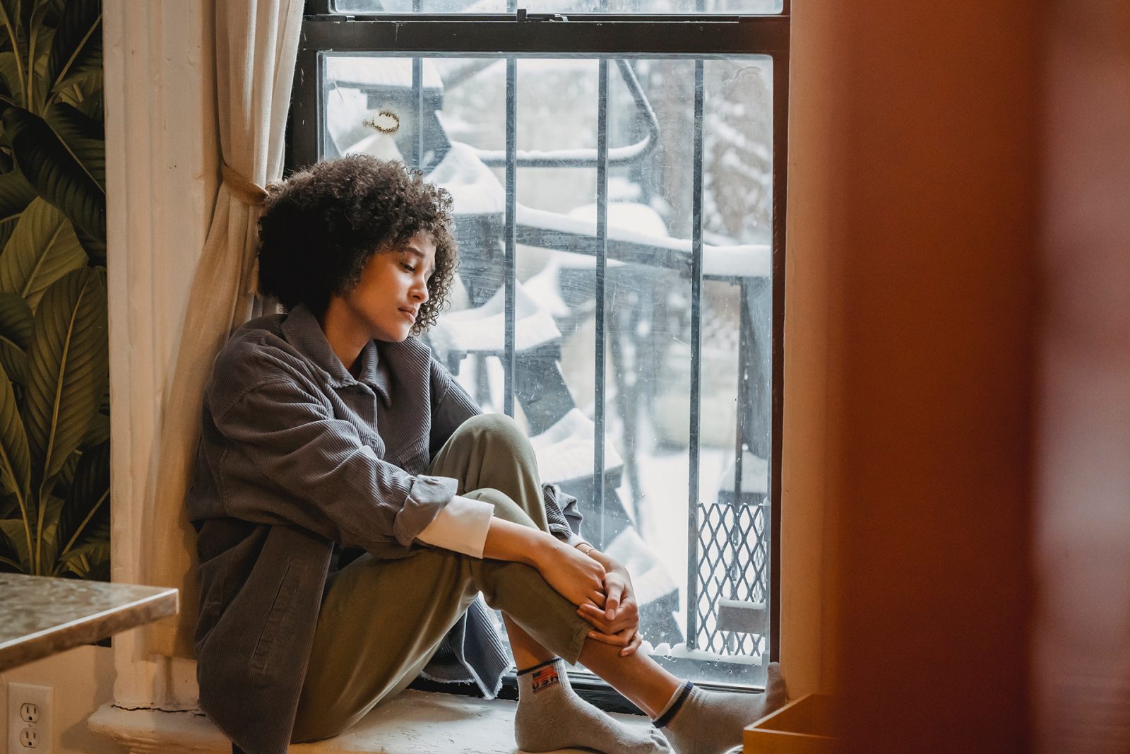 woman sad exhausted sitting at window