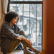 woman sad exhausted sitting at window