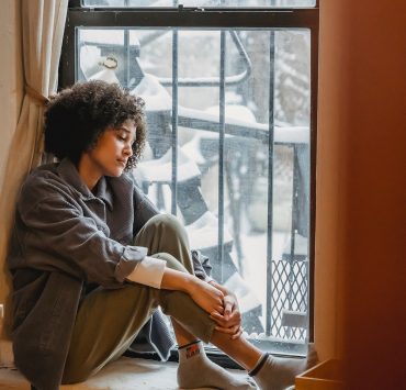 woman sad exhausted sitting at window