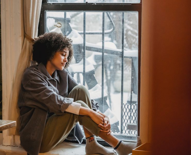 woman sad exhausted sitting at window